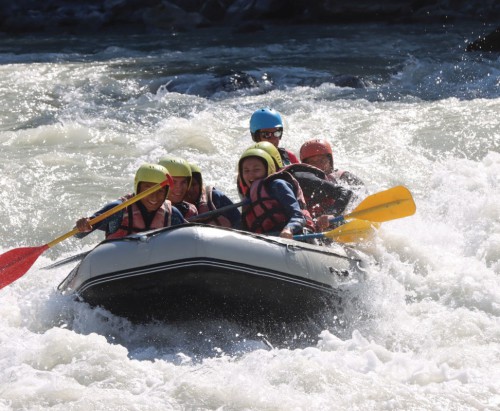 Dans cette photo saisissante, un groupe d'aventuriers se lance dans une descente en rafting sur la rivière Durance, entourée par les paysages grandioses des Hautes-Alpes. Les visages rayonnent d'excitation et d'émerveillement face à la combinaison d'adrén